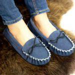 Navy British Made Suede Moccasin Slippers being worn on a brown sheepskin rug